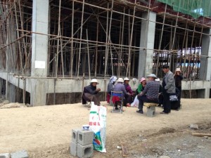 Some of the demonstrators are seen sitting in the premises of the approriated land. Behind them is a partial view of a building under construction.